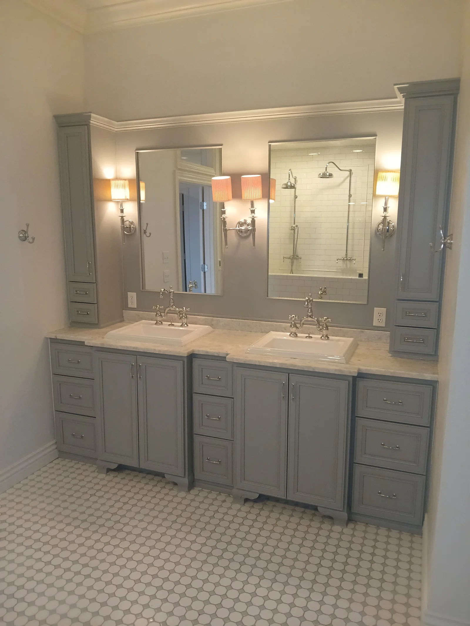 Dual-sink vanity with gray cabinets, marble countertop, framed mirrors, and mosaic tile floor