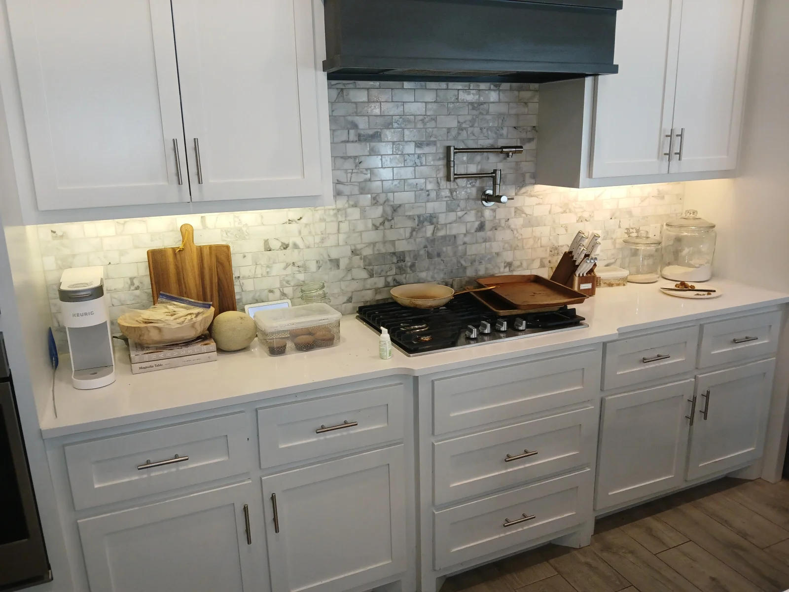 White and gray kitchen with marble subway tile backsplash, quartz counters, and black gas range