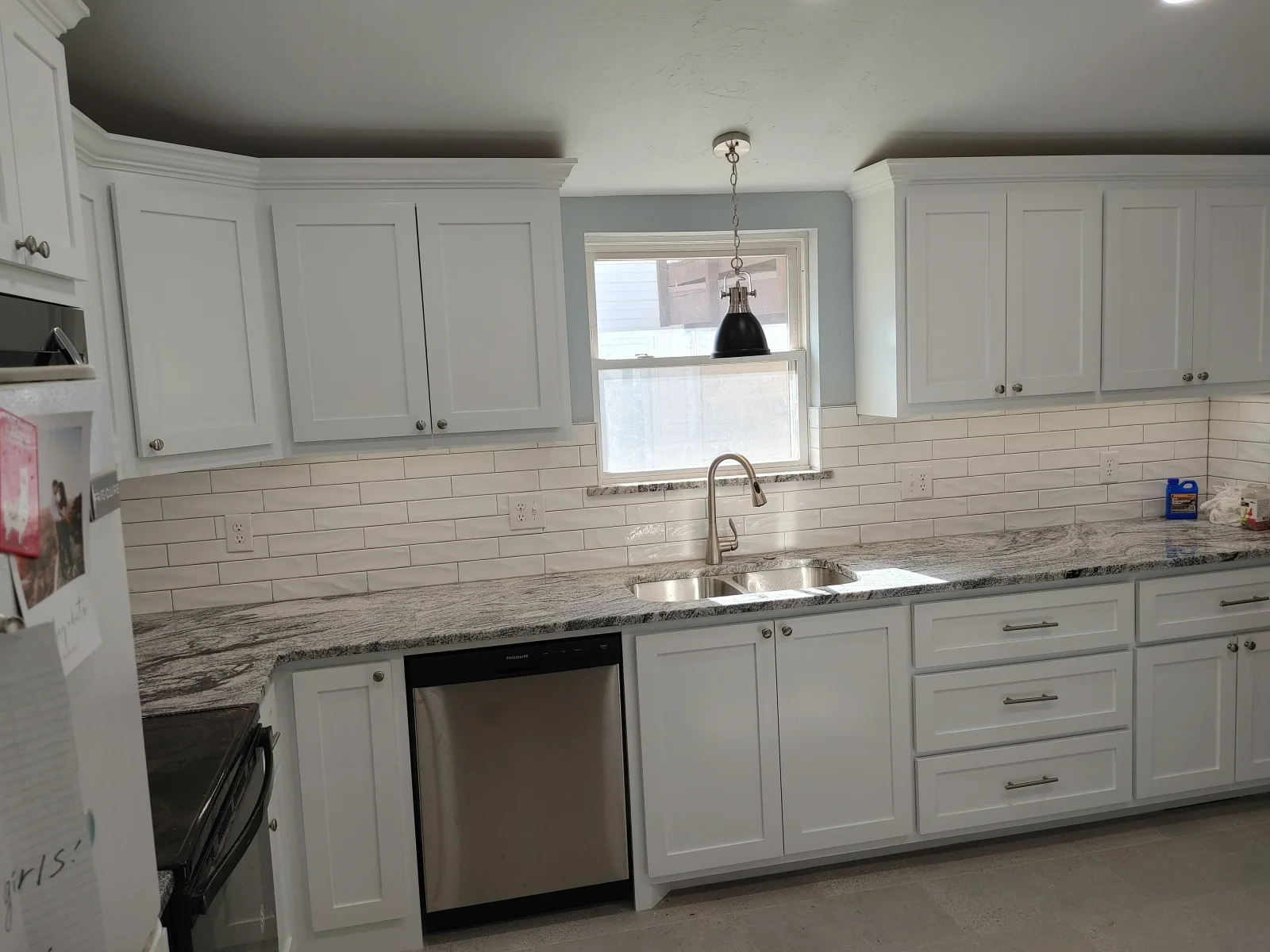 White kitchen cabinets, gray quartz counters, subway tile backsplash, stainless steel sink and appliances