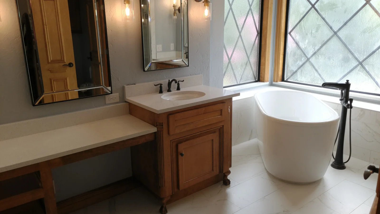 Master bathroom with freestanding tub, wood vanity, quartz counters, and leaded glass windows