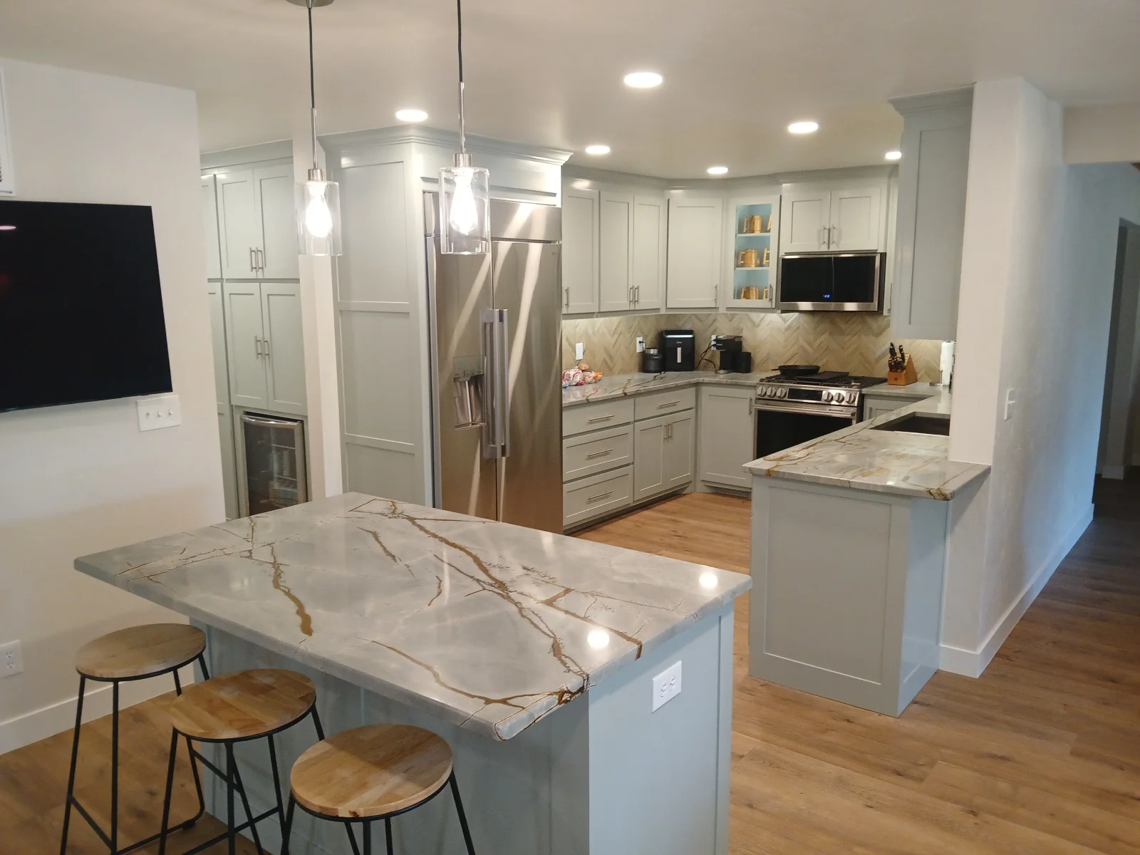 Modern kitchen with white cabinets, quartz countertops, stainless steel appliances, and island seating