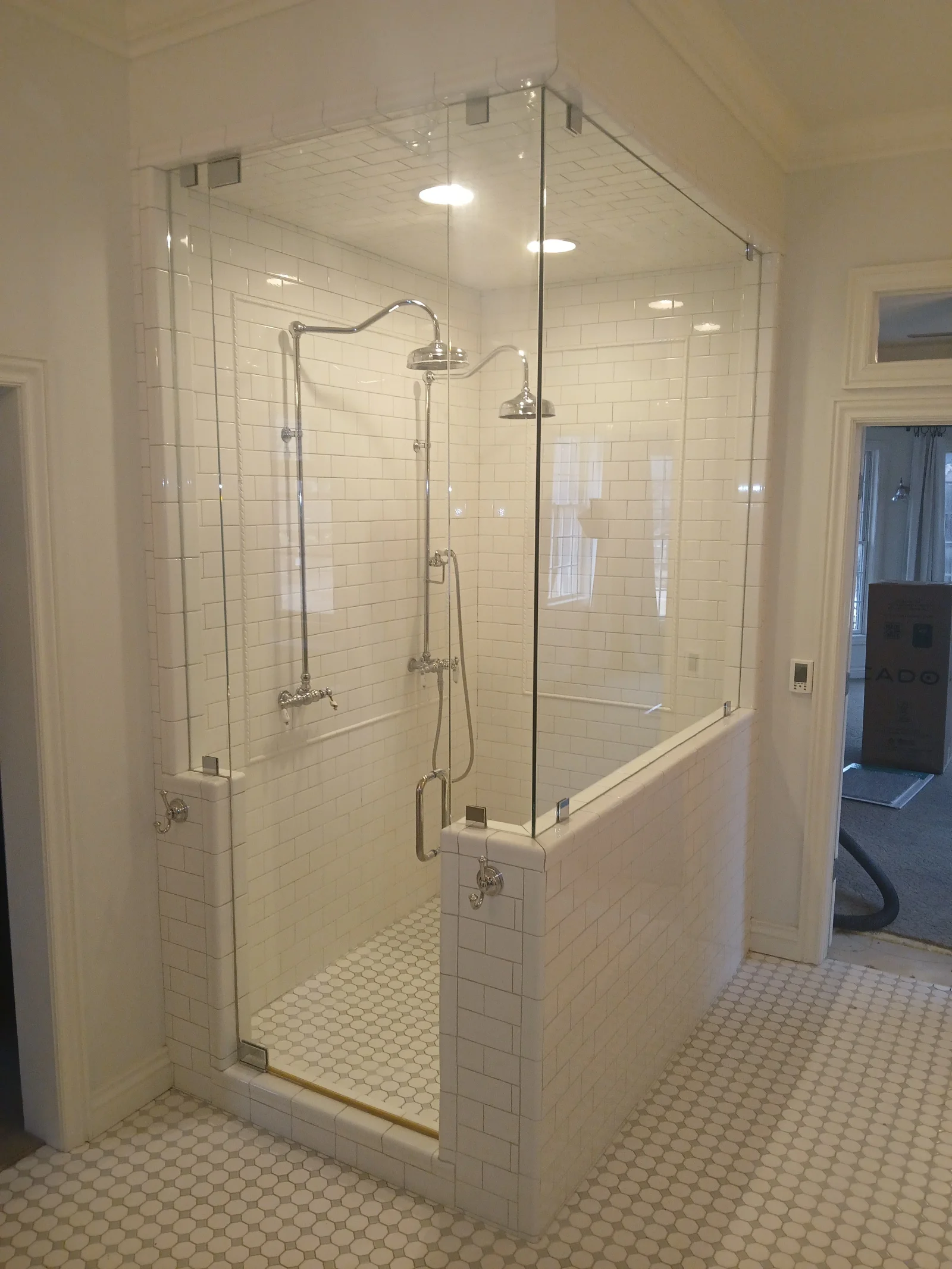 Frameless glass steam shower with subway tile walls, dual showerheads, and mosaic tile floor